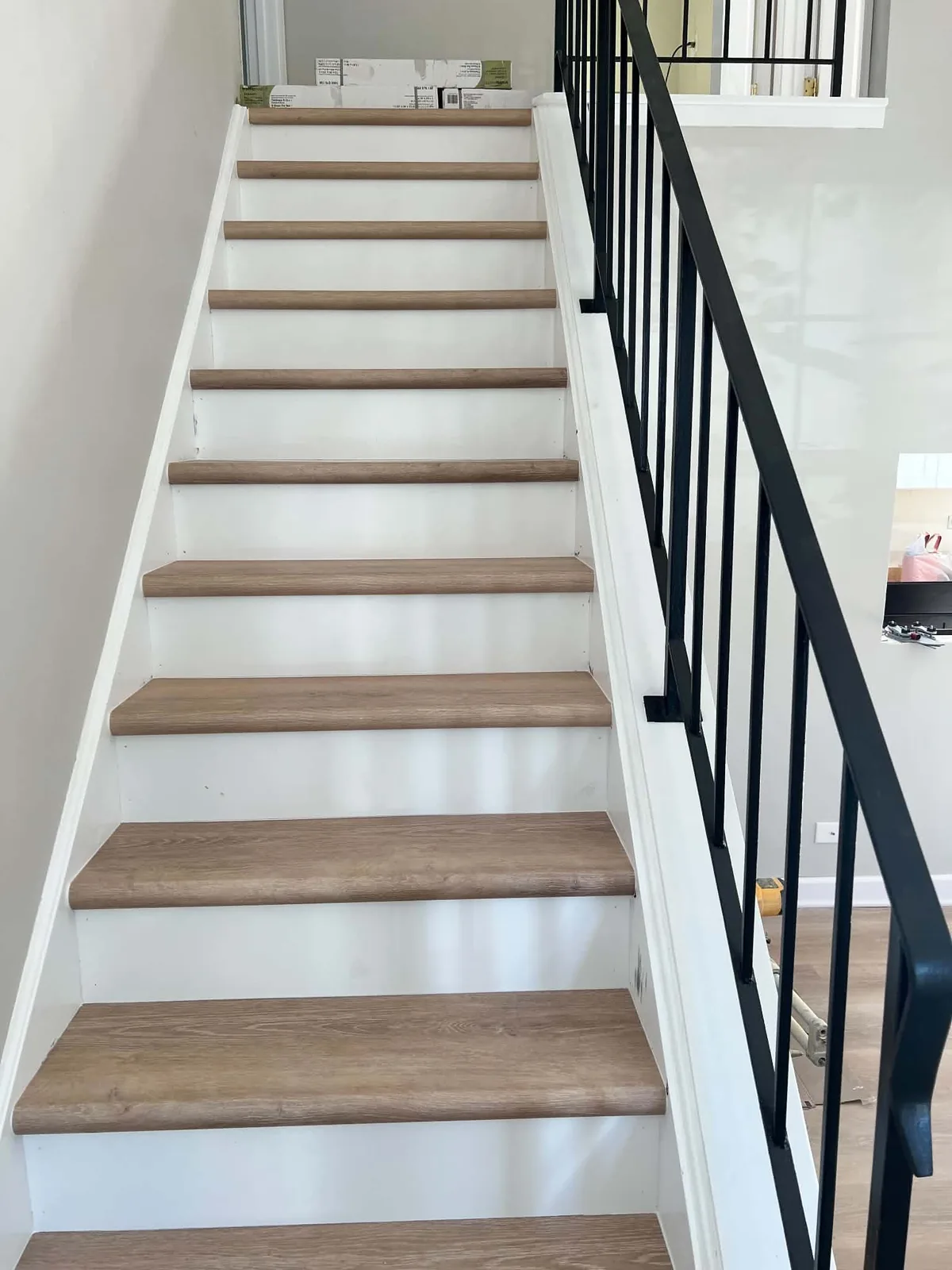 After: bright staircase with wood-look treads, white risers and black railing