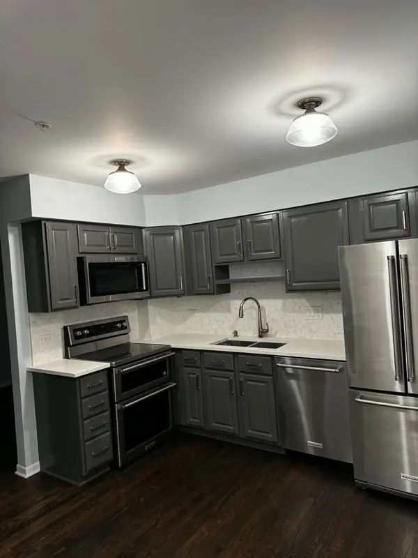 Kitchen with charcoal painted cabinets, white quartz counters and stainless appliances