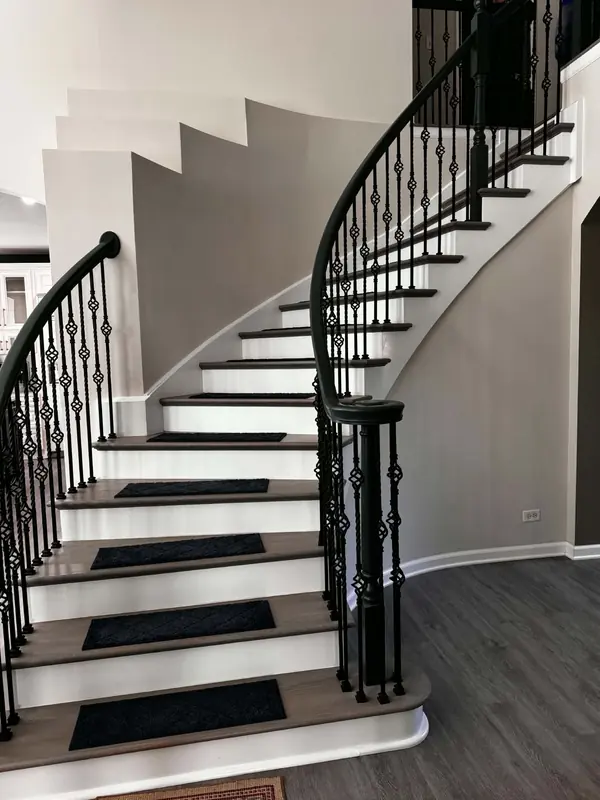 Curved staircase with stained treads, white risers and wrought iron balusters