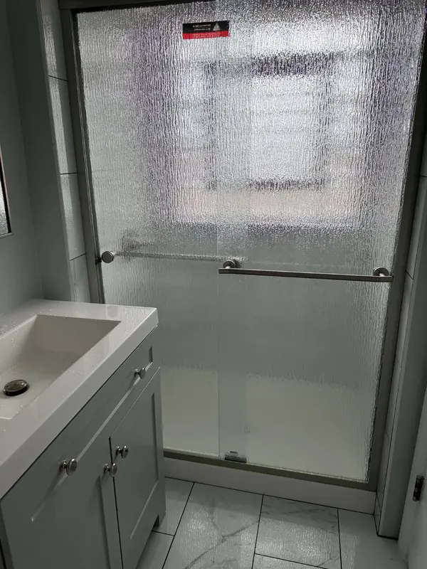 Rain glass sliding shower doors beside a new gray vanity