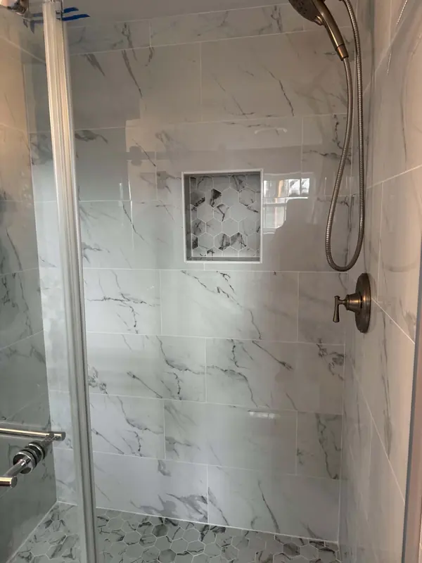 Walk-in shower with white marble-look tile, a hex mosaic niche and bronze fixtures