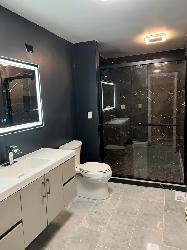 Navy bathroom with floating vanity, LED mirror and a black marble-look walk-in shower