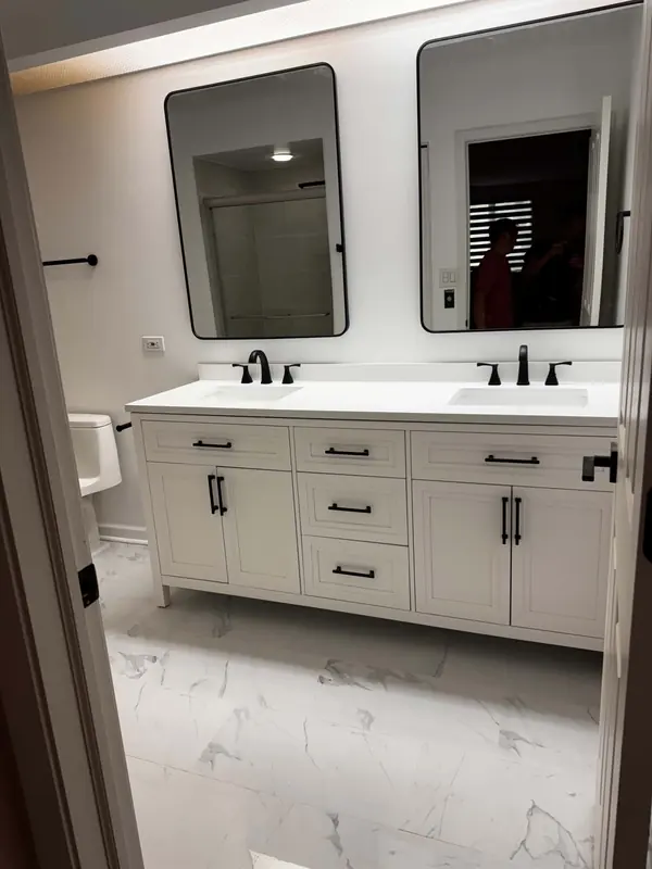 Double vanity with a white quartz top, matte black faucets and framed mirrors