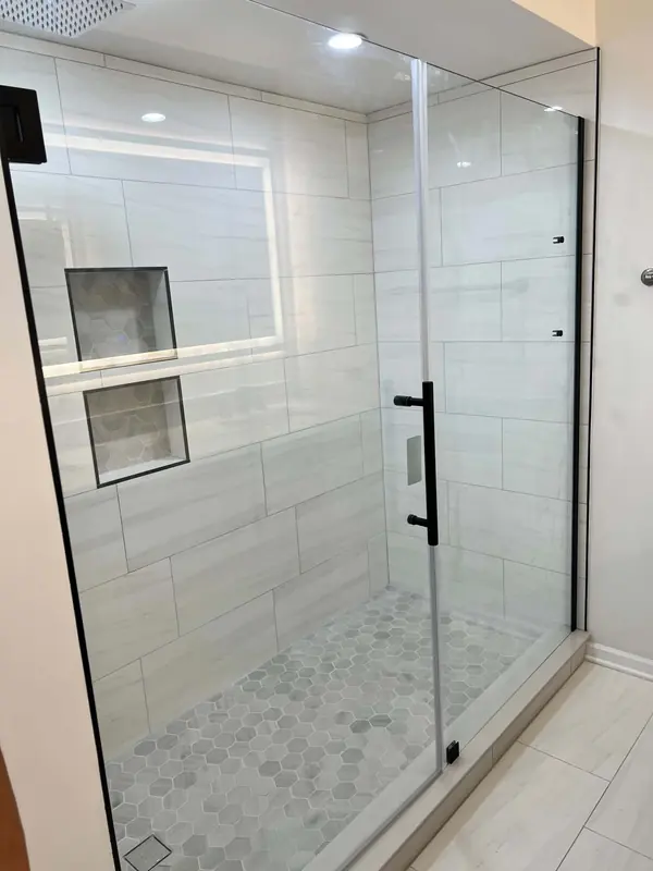 Walk-in shower with frameless glass, white porcelain tile and a hex mosaic floor