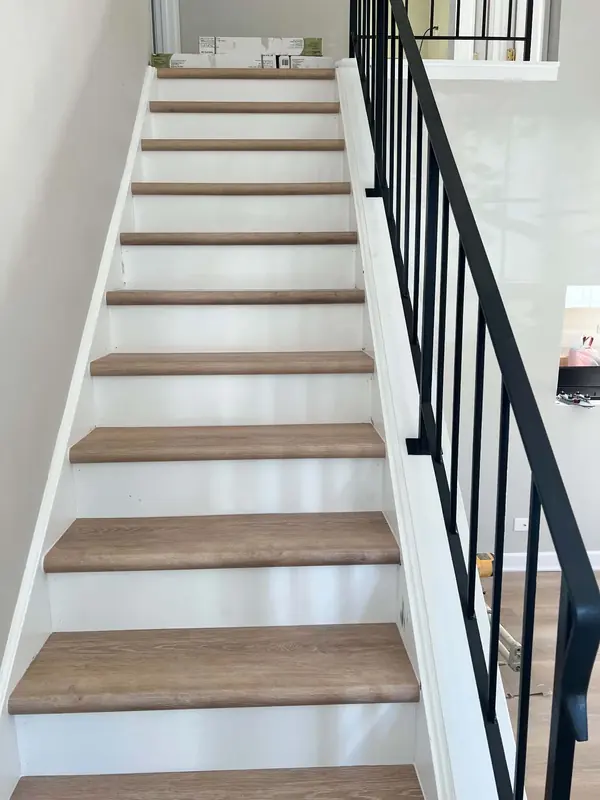 Staircase after: wood-look treads, white risers and a black metal railing
